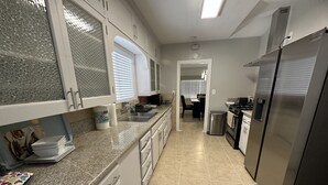 A kitchen with white cabinets, a stainless steel refrigerator, and a tiled floor. - Insta-Worthy! Just Remodeled! Private Home! Luxurious & Brand New  (San Bernardino)