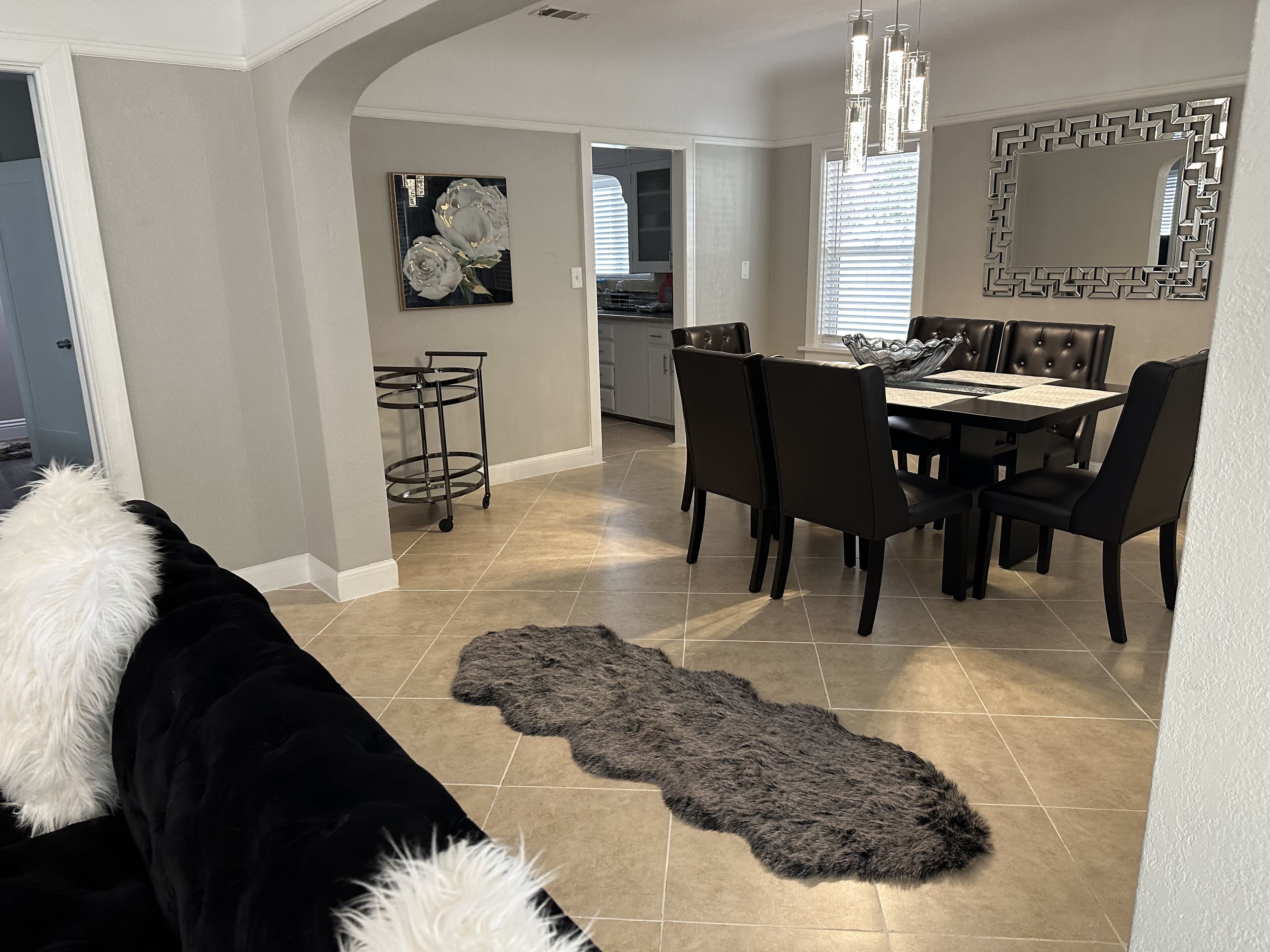Uma sala de jantar com tapete preto e branco, uma mesa e cadeiras.