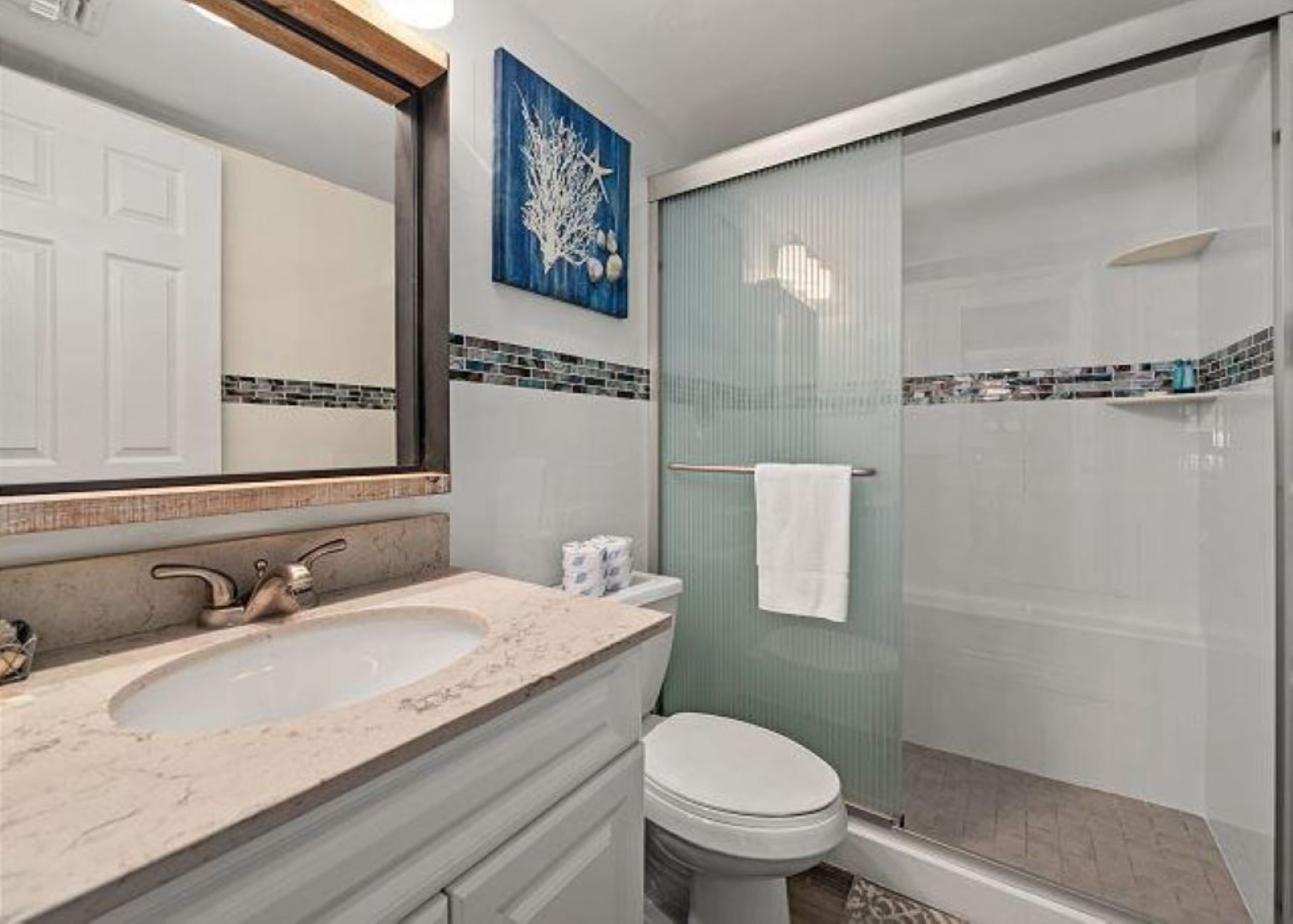 Une salle de bain équipée d’un lavabo, de toilettes et d’une douche à parois en verre.