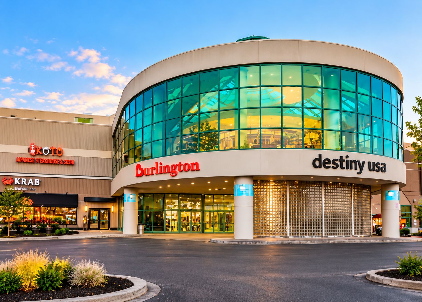 Un edificio moderno con fachada de vidrio curva, que muestra los logotipos de Burlington y Destiny USA.