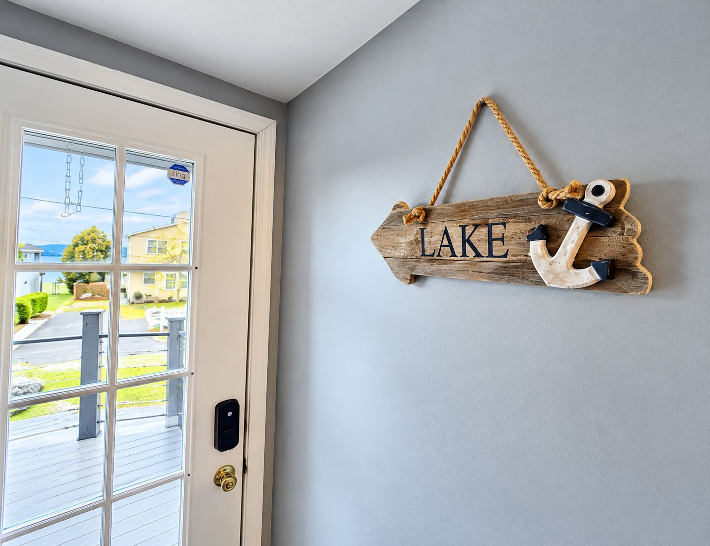 A wooden sign with the word 'LAKE' and an anchor hanging on a wall.