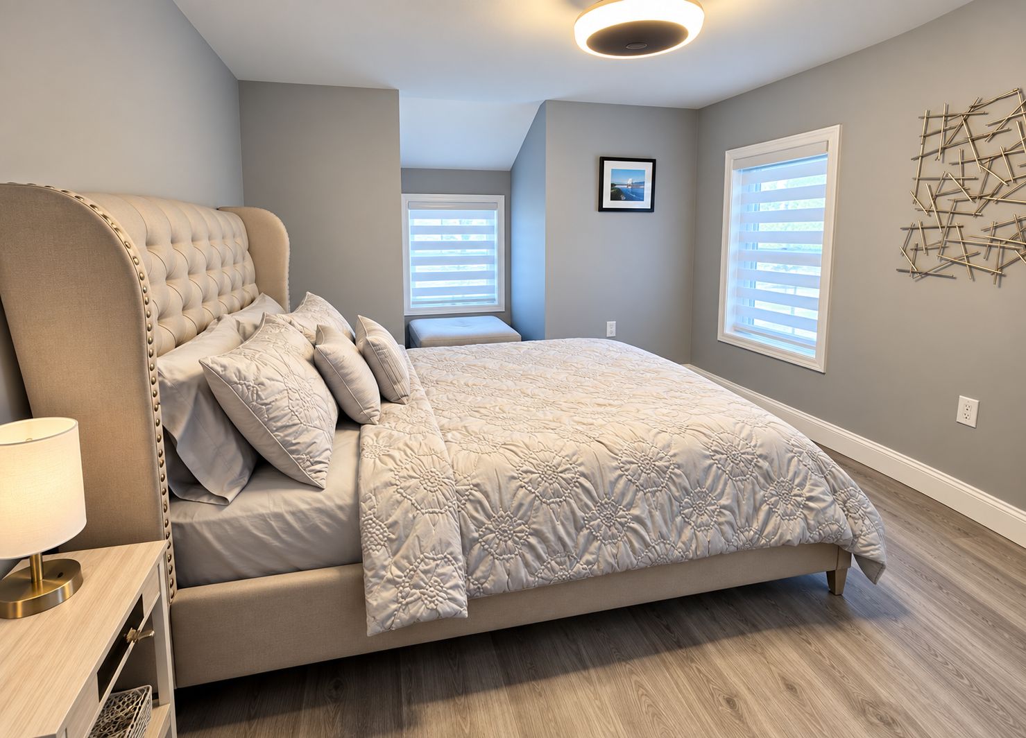 A bedroom with a large bed, a bedside table, and a wall-mounted light fixture.
