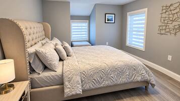A bedroom with a large bed, a bedside table, and a wall-mounted light fixture.