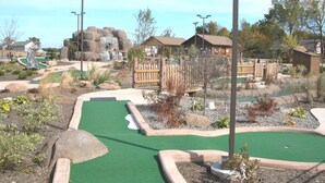 Un parcours de minigolf doté d’une zone d’entraînement au putting en gazon, d’un aménagement paysager et de structures en bois.