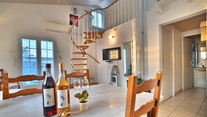 En matplats med ett träbord, två vinflaskor och en krukväxt. I bakgrunden syns en spiraltrappa.