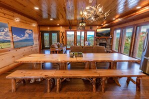 Un intérieur en bois avec une grande table à manger, des bancs, un canapé et une cheminée.