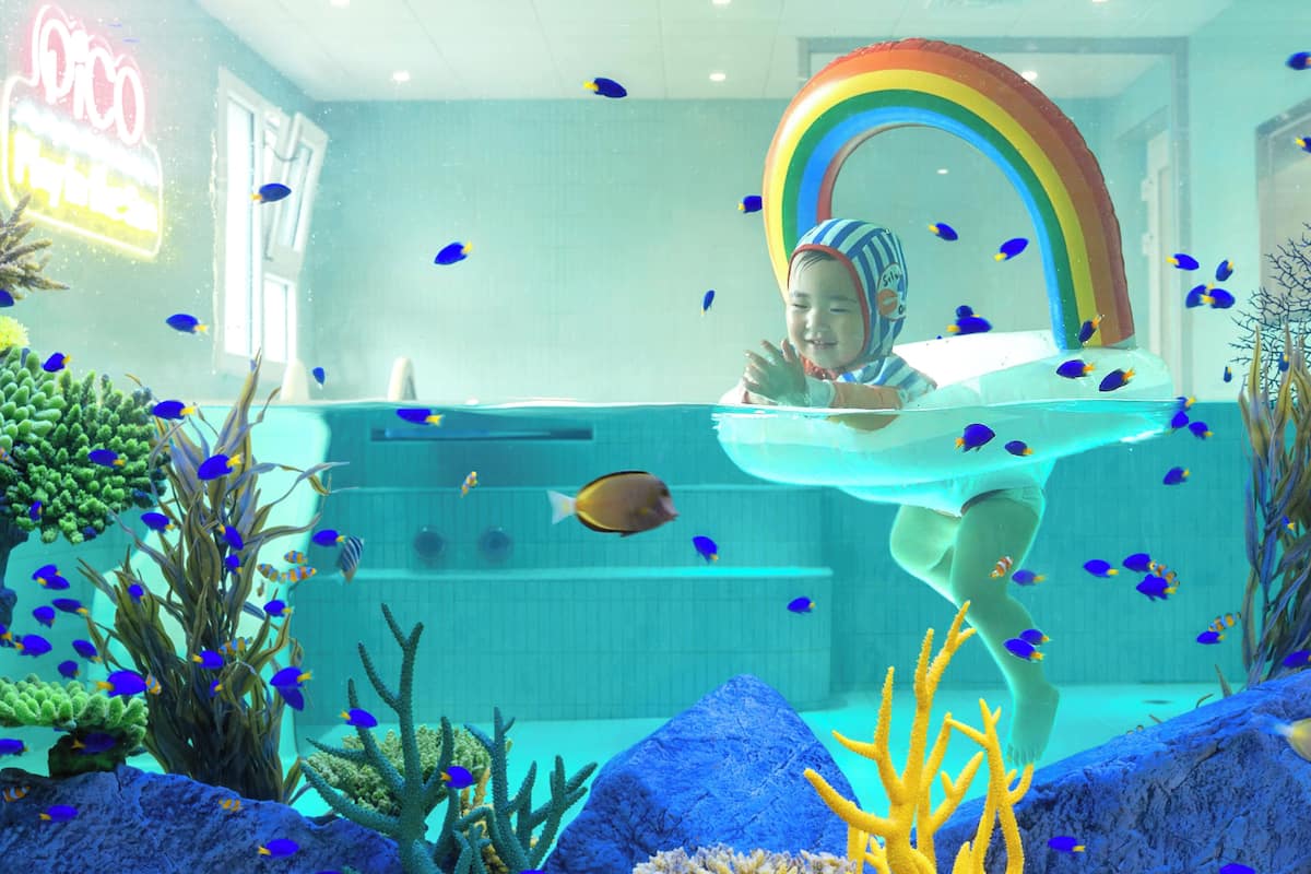 Escena submarina con una persona, peces y un arcoíris.
