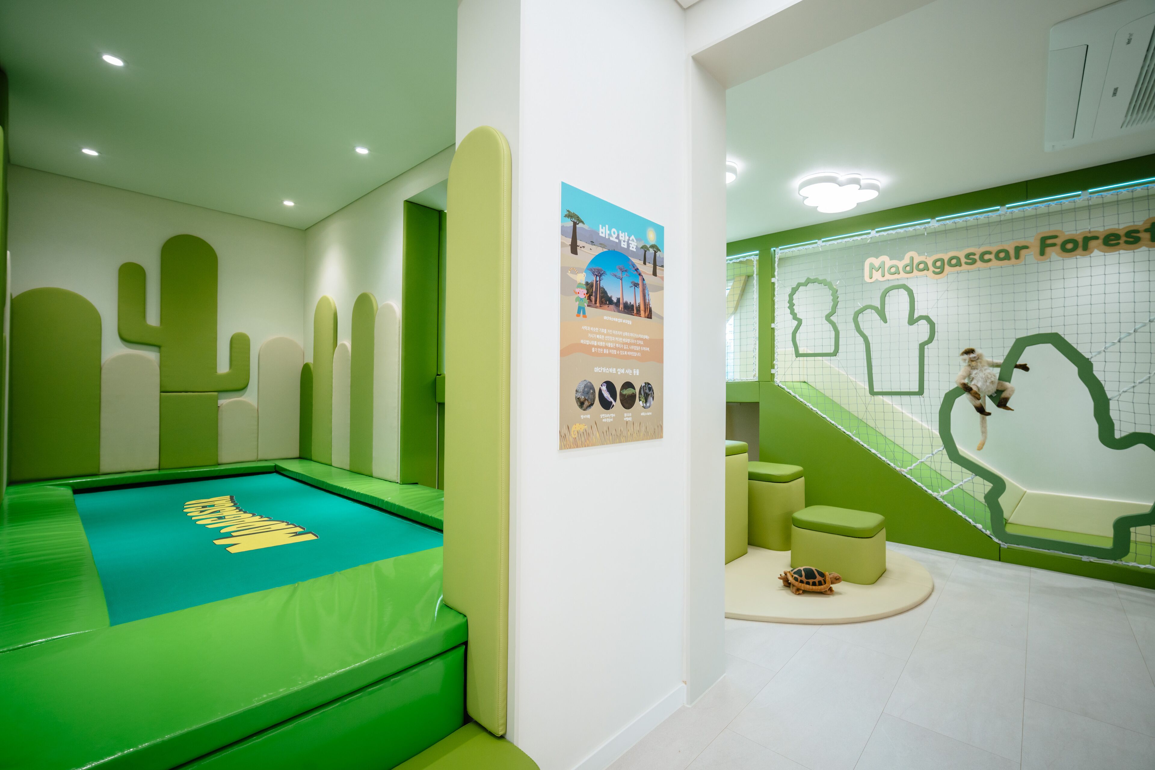 A children's play area with green flooring and cacti wall decorations.