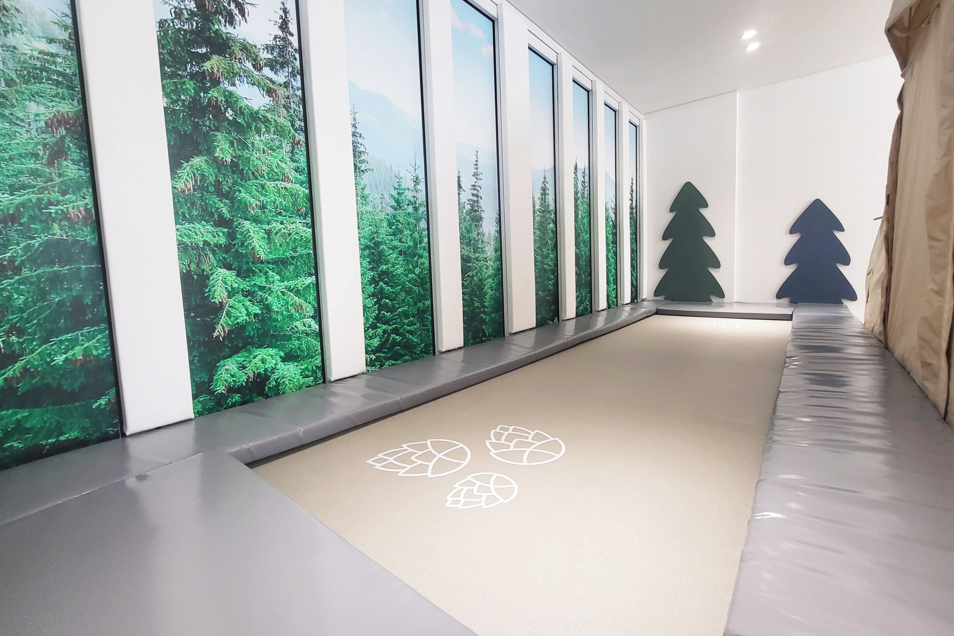 A hallway with large windows, a tatami mat floor, and a wall with a forest mural.
