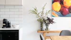 Una cocina moderna con una cafetera, un tazón y un florero con plantas sobre una mesa de madera.