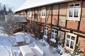 Ein traditionelles Fachwerkhäuschen mit schneebedecktem Untergrund und einer hölzernen Bank.