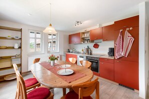 Une cuisine moderne avec des chaises en bois, une table à manger et des armoires rouges.