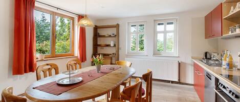A dining area with a wooden table, chairs, and a hanging light fixture.