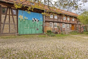 Il s’agit d’un bâtiment traditionnel doté d’une porte de garage verte, d’un sol pavé et d’une structure à deux étages avec des fenêtres apparentes et une porte en bois.