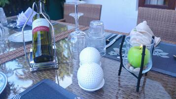 Une table à manger dressée avec une bouteille de vin, des verres à vin et un porte-bougie décoratif surmonté d’une pomme.