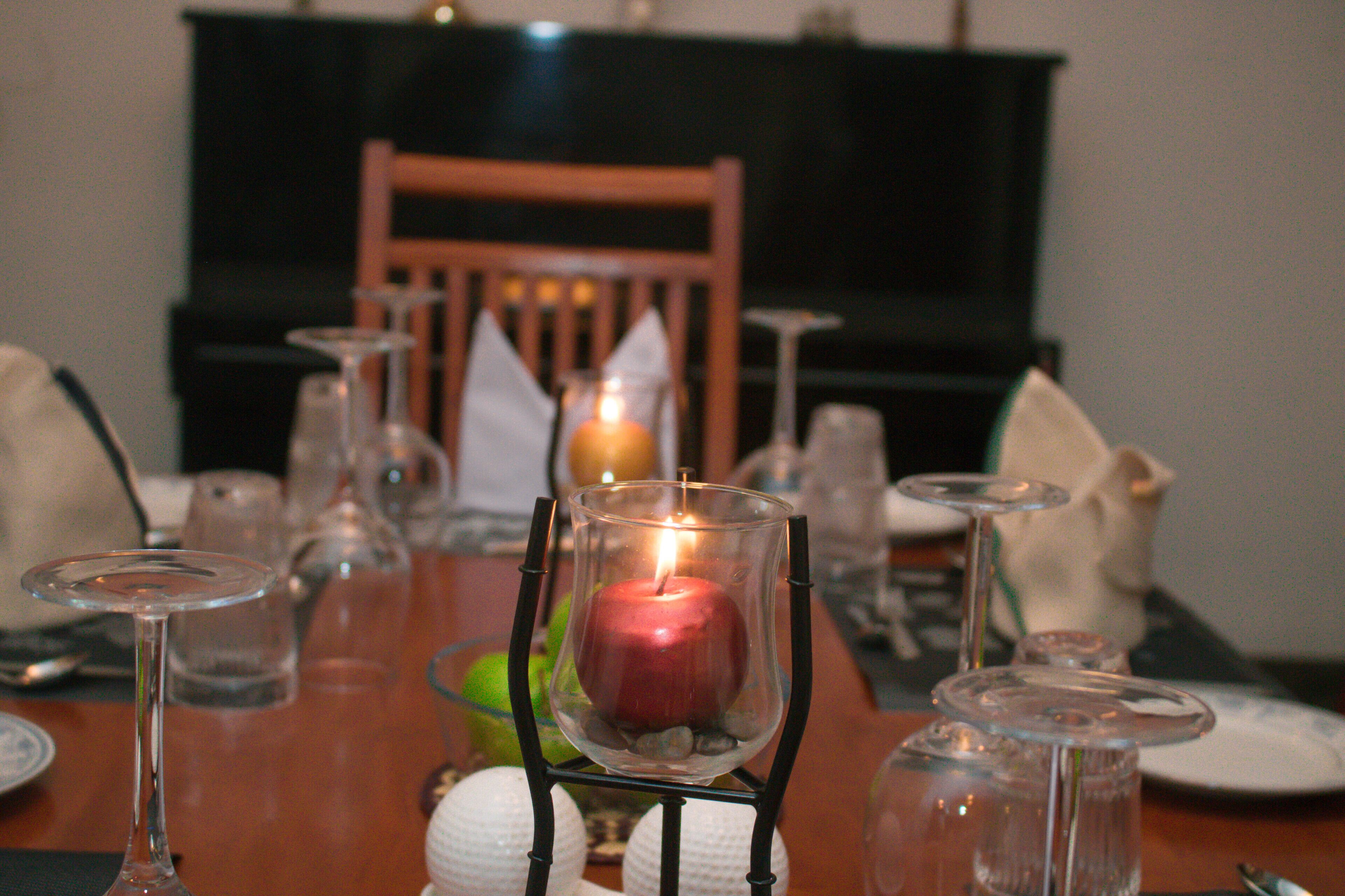 Une table à manger ornée d’un chandelier avec une bougie, entourée de verres à vin et d’assiettes.
