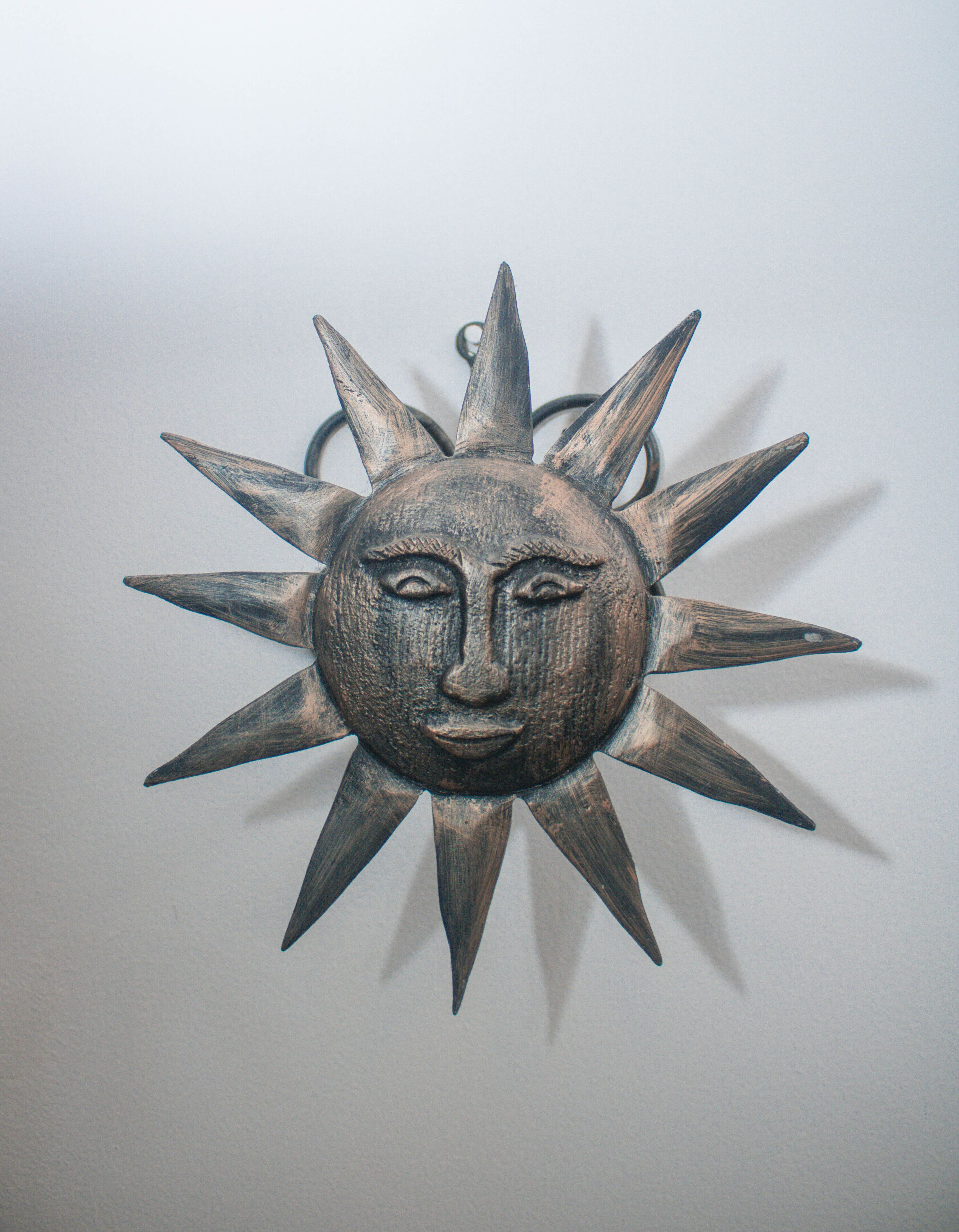 Un adorno de sol sujeto a la pared, con un rostro en el centro.