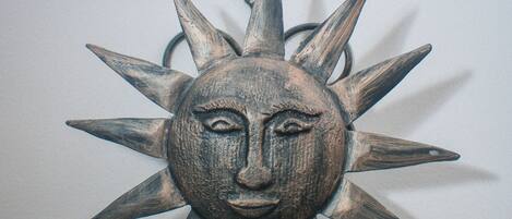 A wall-mounted sun decoration with a face in the center.