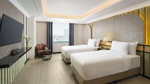 Een hotelkamer met twee bedden, een televisie, een klein tafeltje met een stoel en uitzicht op de stad.