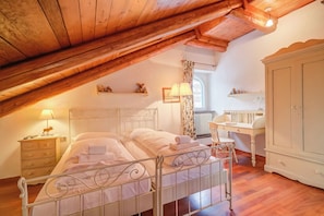 A bedroom with a sloped ceiling, a bed, a nightstand, a dresser, and a window with curtains. - La Torre In The Center Of Town (Sauze d'Oulx)