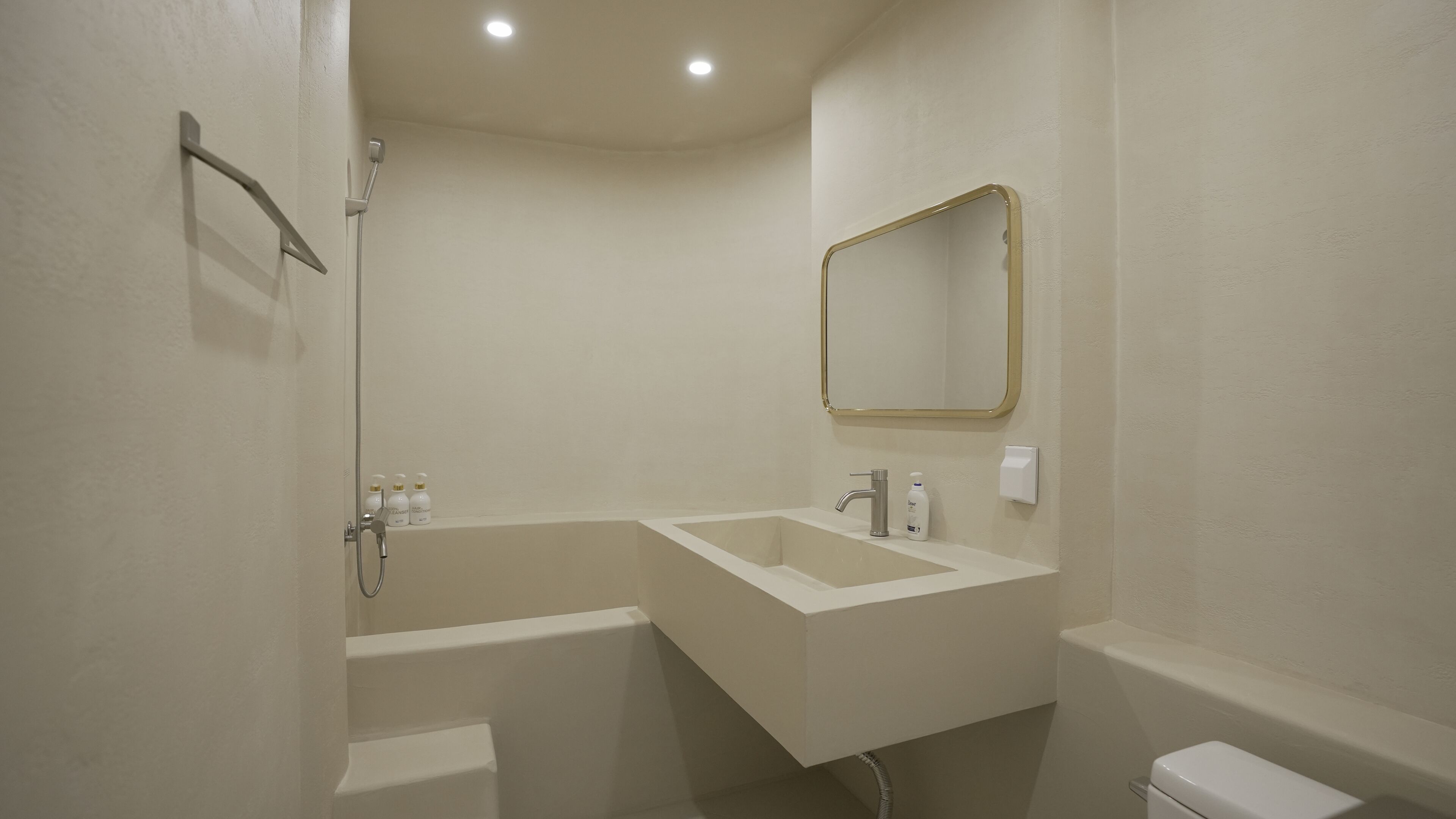 Une salle de bain avec un lavabo blanc, un miroir et des toilettes.