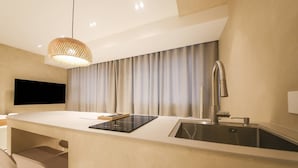 Una cocina moderna con un lavaplatos empotrado, un televisor de pantalla plana en la pared y una lámpara colgante.