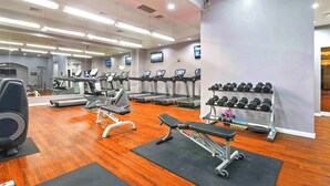 Une salle de sport équipée de tapis de course, de bancs de musculation et d’une série d’haltères.