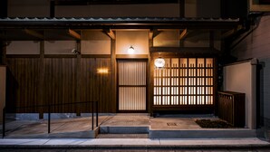 Ein traditioneller japanischer Eingangsbereich mit Holztür, Laterne und einer Schiebetür.