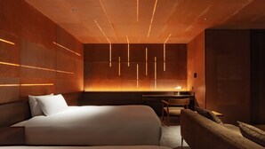 Ein modernes Hotelzimmer mit zwei Betten, einem Schreibtisch und einem Sofa.
