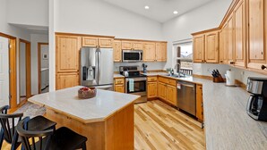 A modern kitchen with wooden cabinets, stainless steel appliances, and a large island. - Modern Lodge with a Jacuzzi Tub (Bend)