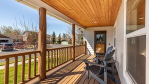 A wooden deck with a railing, a bench, and a door leading to a covered porch. - Modern Lodge with a Jacuzzi Tub (Bend)