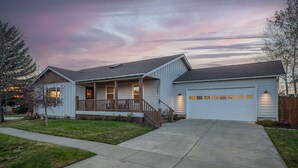 A single-story house with a front porch, a garage, and a well-maintained lawn. - Modern Lodge with a Jacuzzi Tub (Bend)