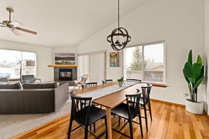 A modern living room with a fireplace, dining area, and large windows. - Modern Lodge with a Jacuzzi Tub (Bend)