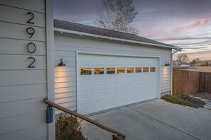 A residential garage with a white door, a metal number '2902' sign, and a wooden handrail. - Modern Lodge with a Jacuzzi Tub (Bend)