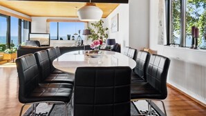 A modern dining area with a round table and black leather seating.