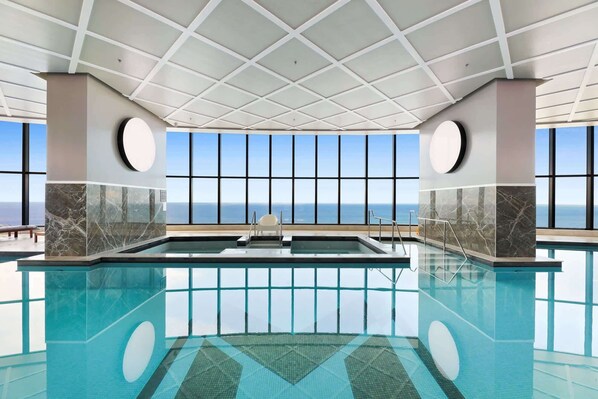 A large indoor swimming pool with a clear view of the ocean through large windows. - Luxe Oceanfront 1-Bed High Rise with Pool & Gym (Surfers Paradise)