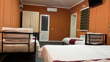 A hotel room with two beds, a wardrobe, a television, and an air conditioning unit.