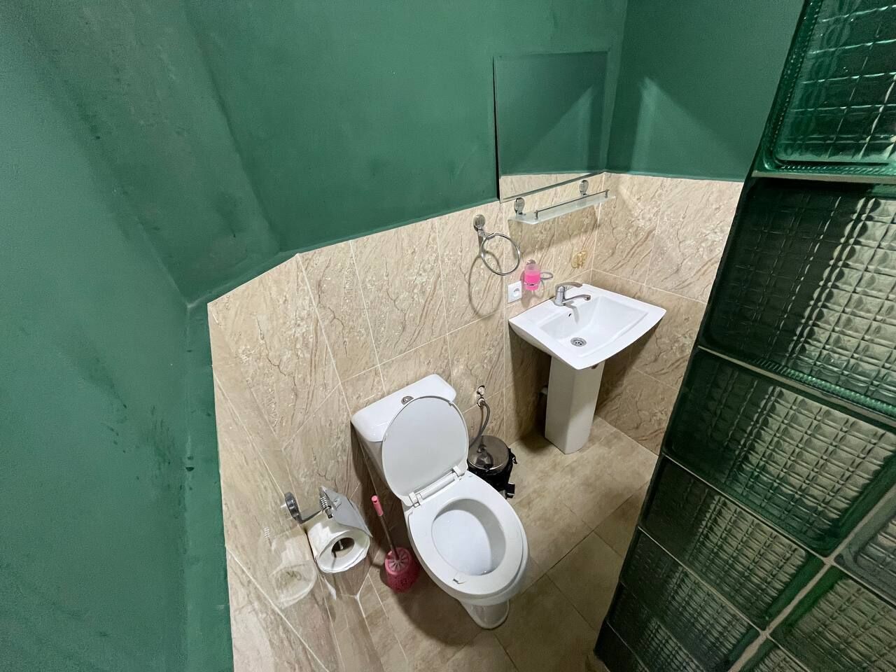 A bathroom with a toilet, sink, and a mirror.