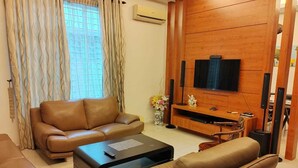 A living room with a sofa, a coffee table, and a TV mounted on a wooden wall. - Nice semi D house at Tangkak (Tangkak)