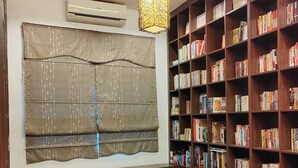 A cozy reading nook with a large bookshelf, a hanging light fixture, and a window with a decorative blind. - Nice semi D house at Tangkak (Tangkak)
