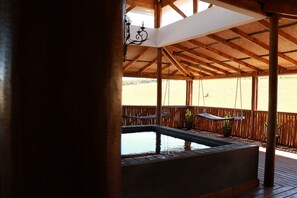 A covered outdoor area with a hot tub, wooden deck, and hanging hammocks. - Bon Game Reserve (Albertinia)
