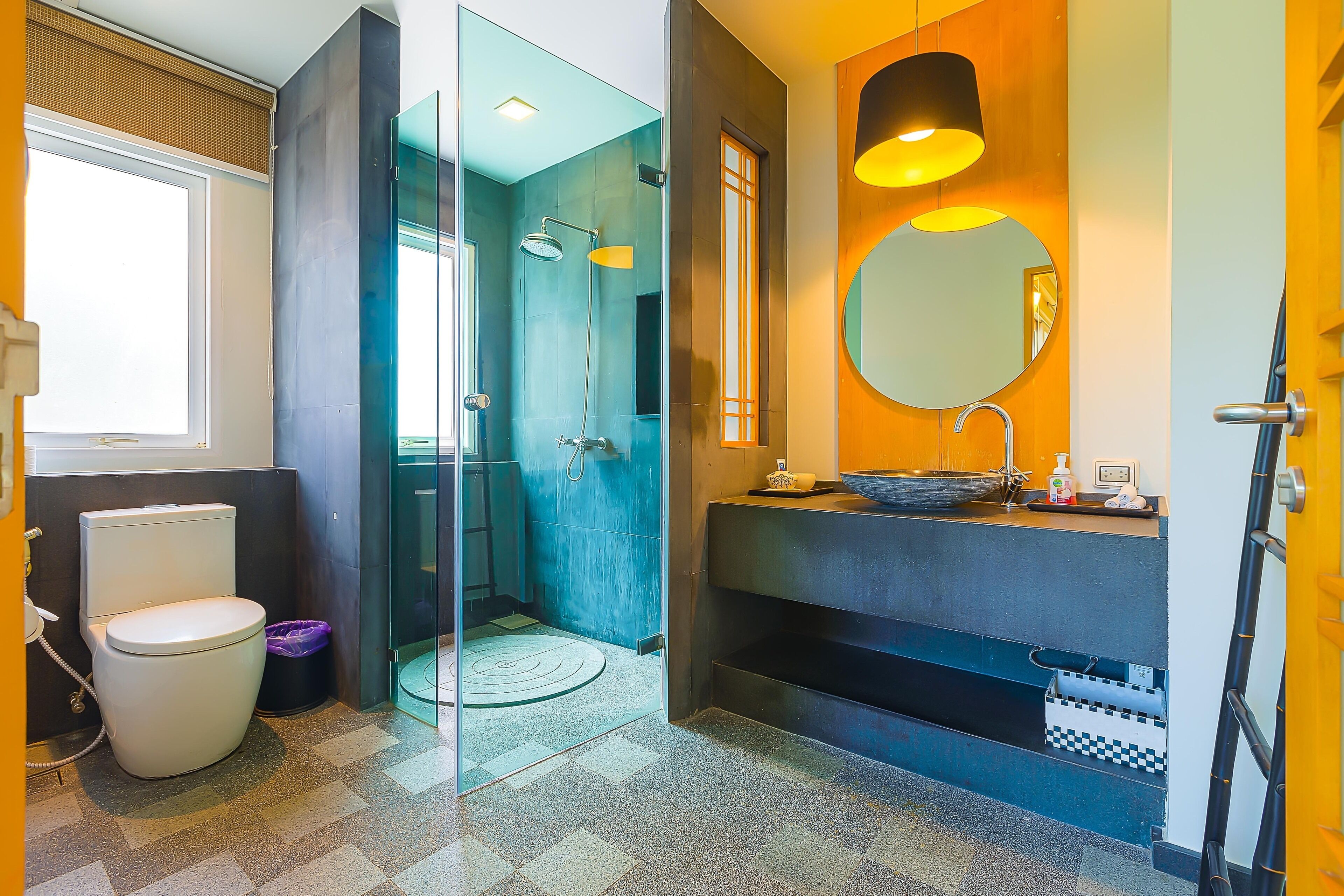 A modern bathroom with a toilet, a glass-enclosed shower, a sink with a mirror, and a towel rack.