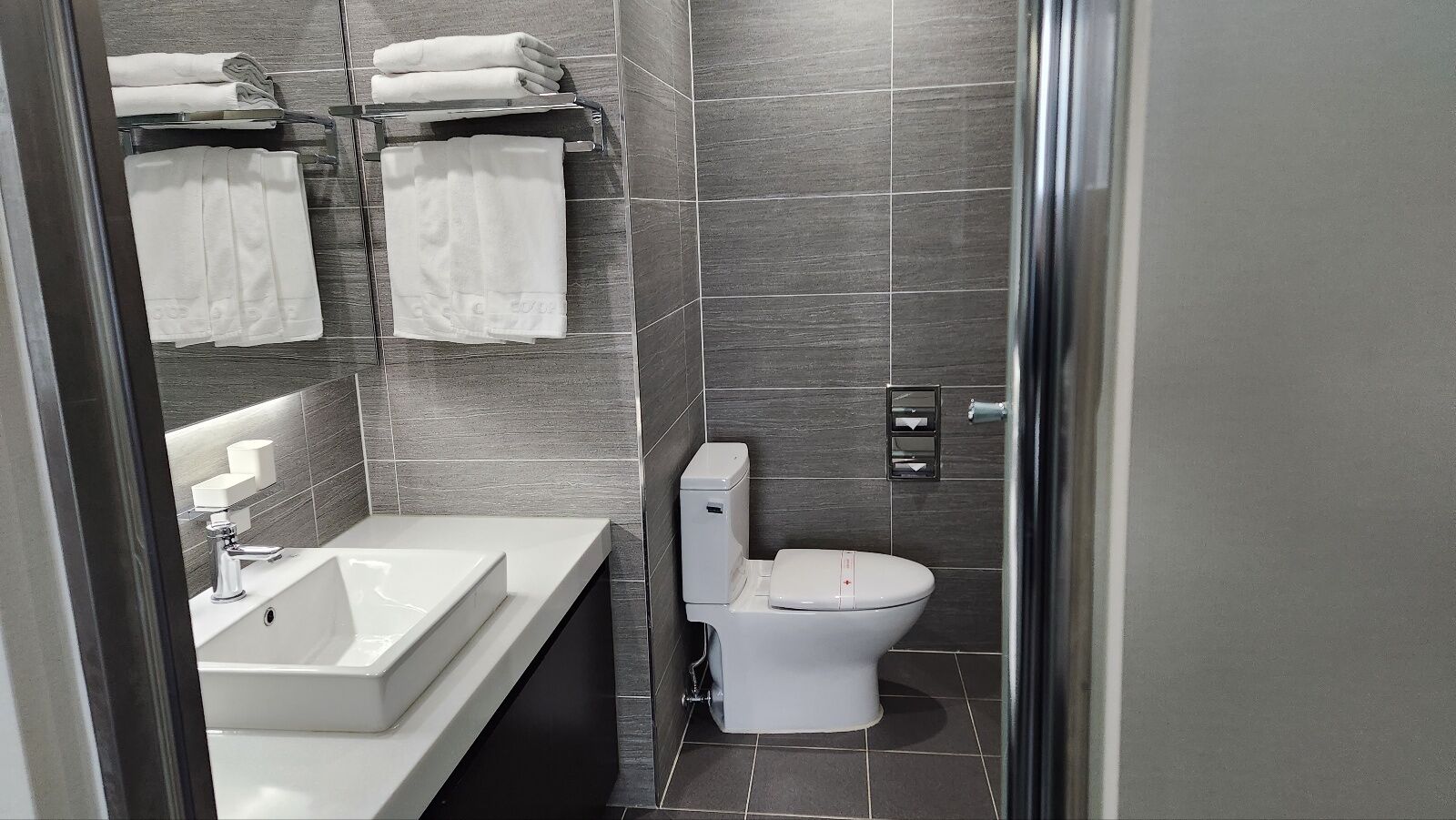 A modern bathroom with a white sink, toilet, and towel rack.