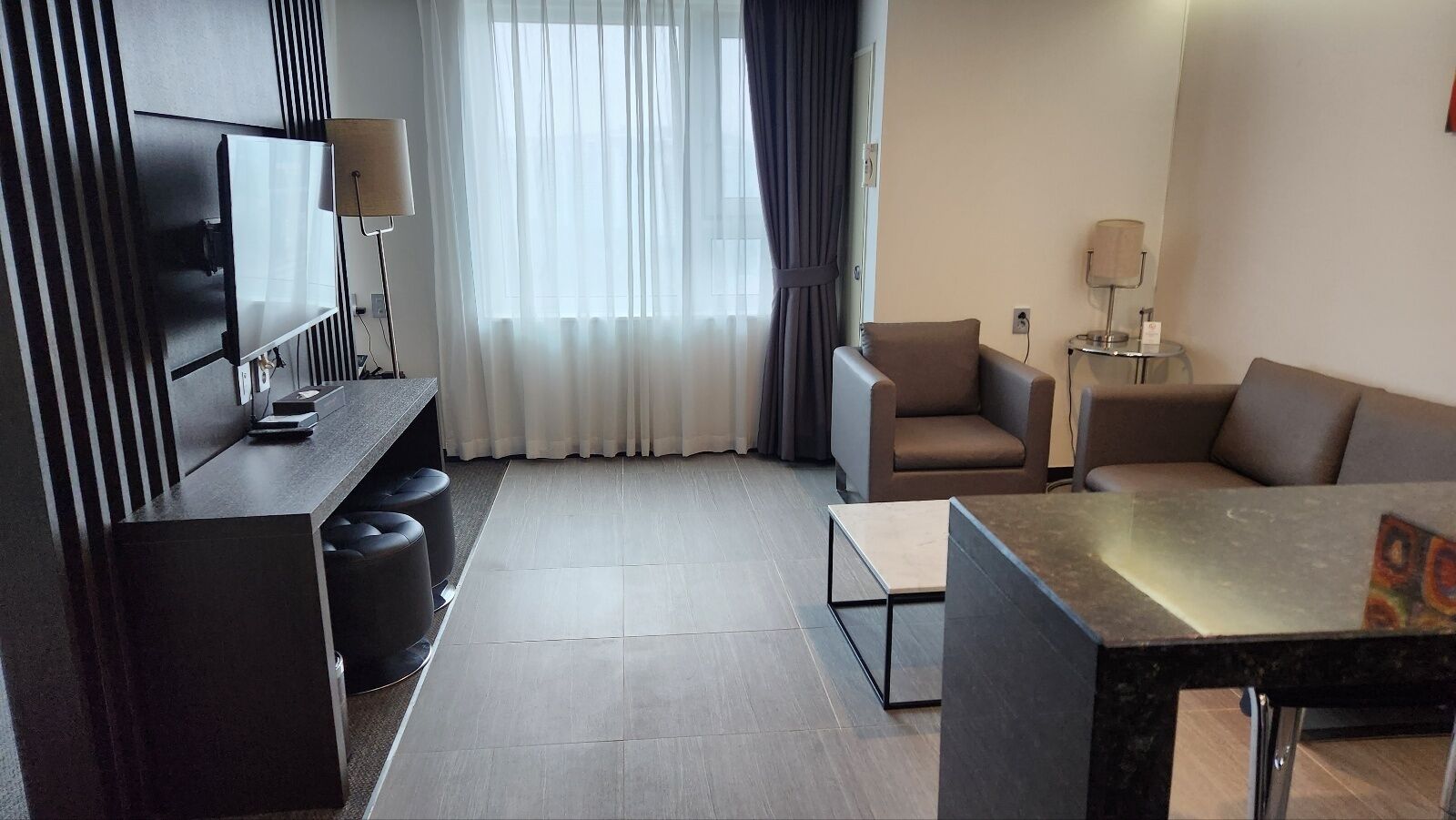 A modern living room with a flat-screen TV, a sofa, a coffee table, and a TV stand with a lamp.