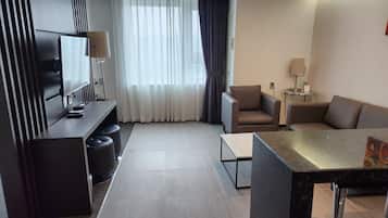 A modern living room with a flat-screen TV, a sofa, a coffee table, and a TV stand with a lamp.