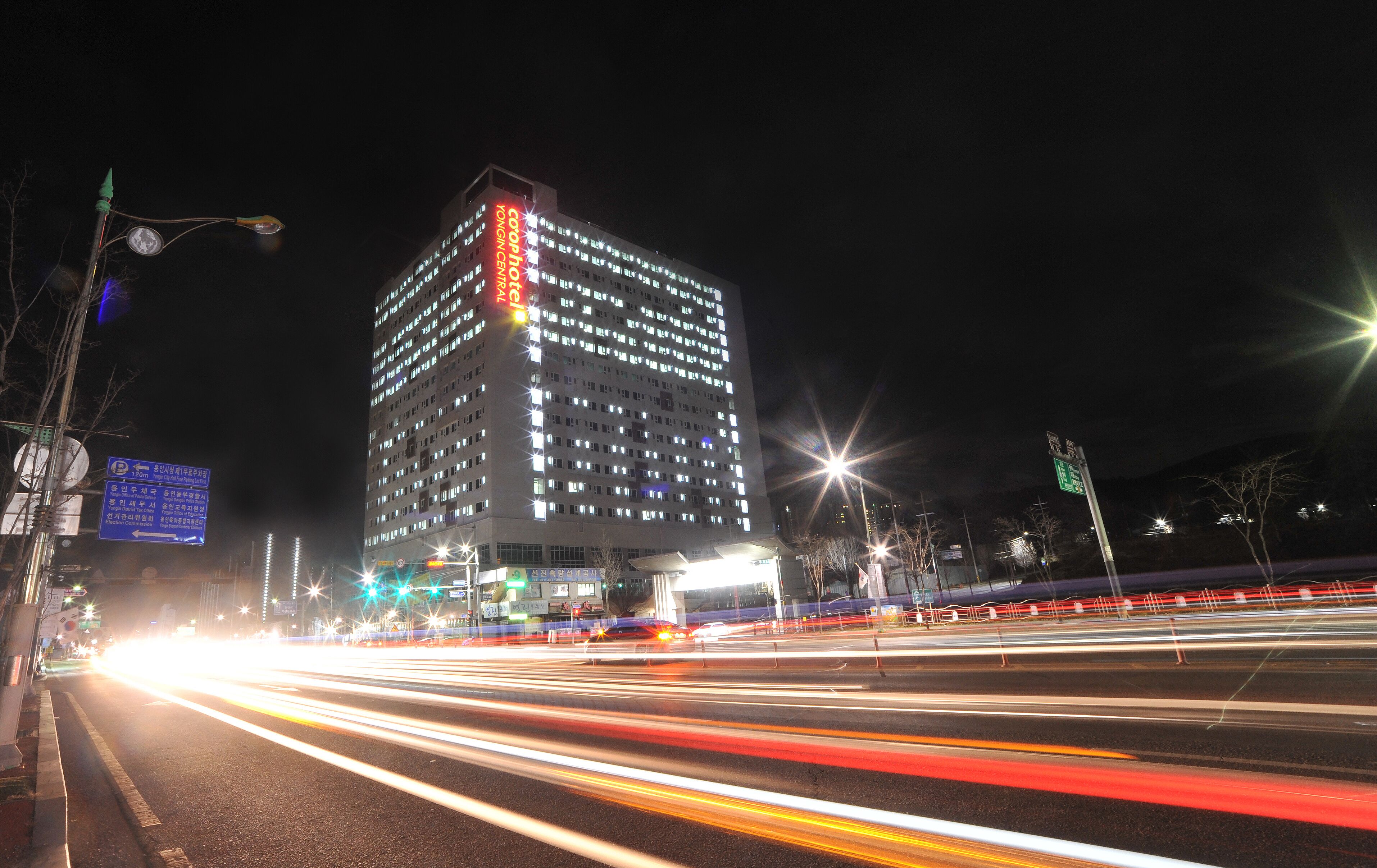A high-rise building with illuminated signage at night, featuring a prominent red and white sign.