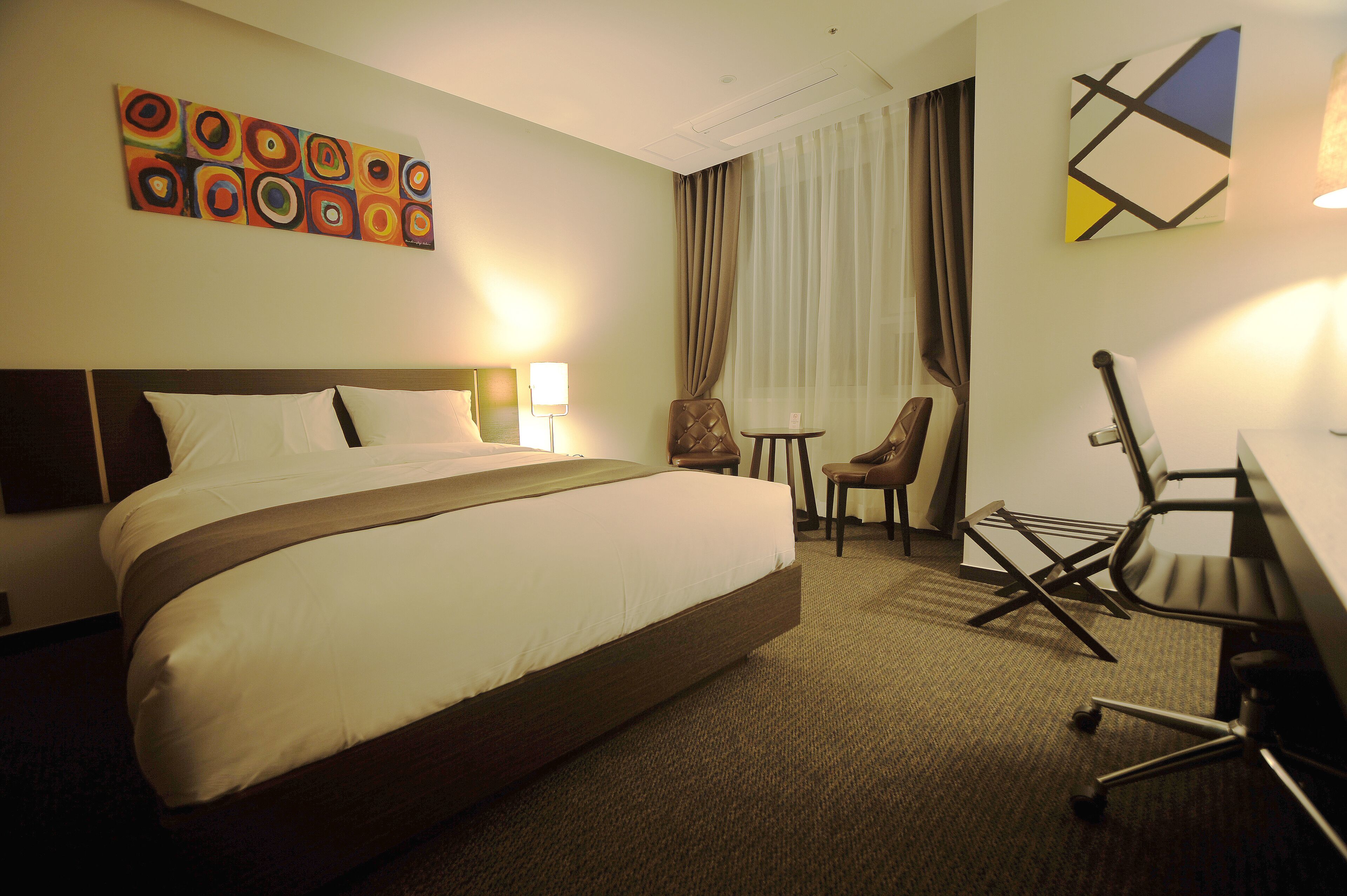 Ein Hotelzimmer mit einem großen Bett, einem Schreibtisch, einem Sessel und einem kleinen Tisch.