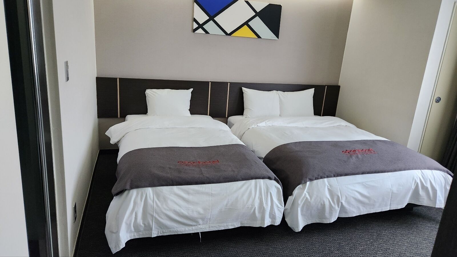 A double room with two beds, each with white linens and gray throw blankets.