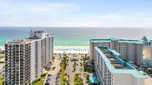 Een strandhotel met meerdere hoge gebouwen, een parkeerplaats en een strand op de achtergrond.