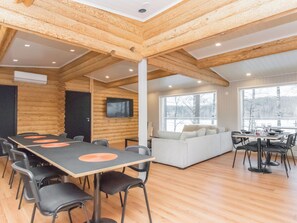 A log cabin interior with a dining area, a sofa, and a TV mounted on the wall. - Villa lahnajärvi by Interhome (Salo)